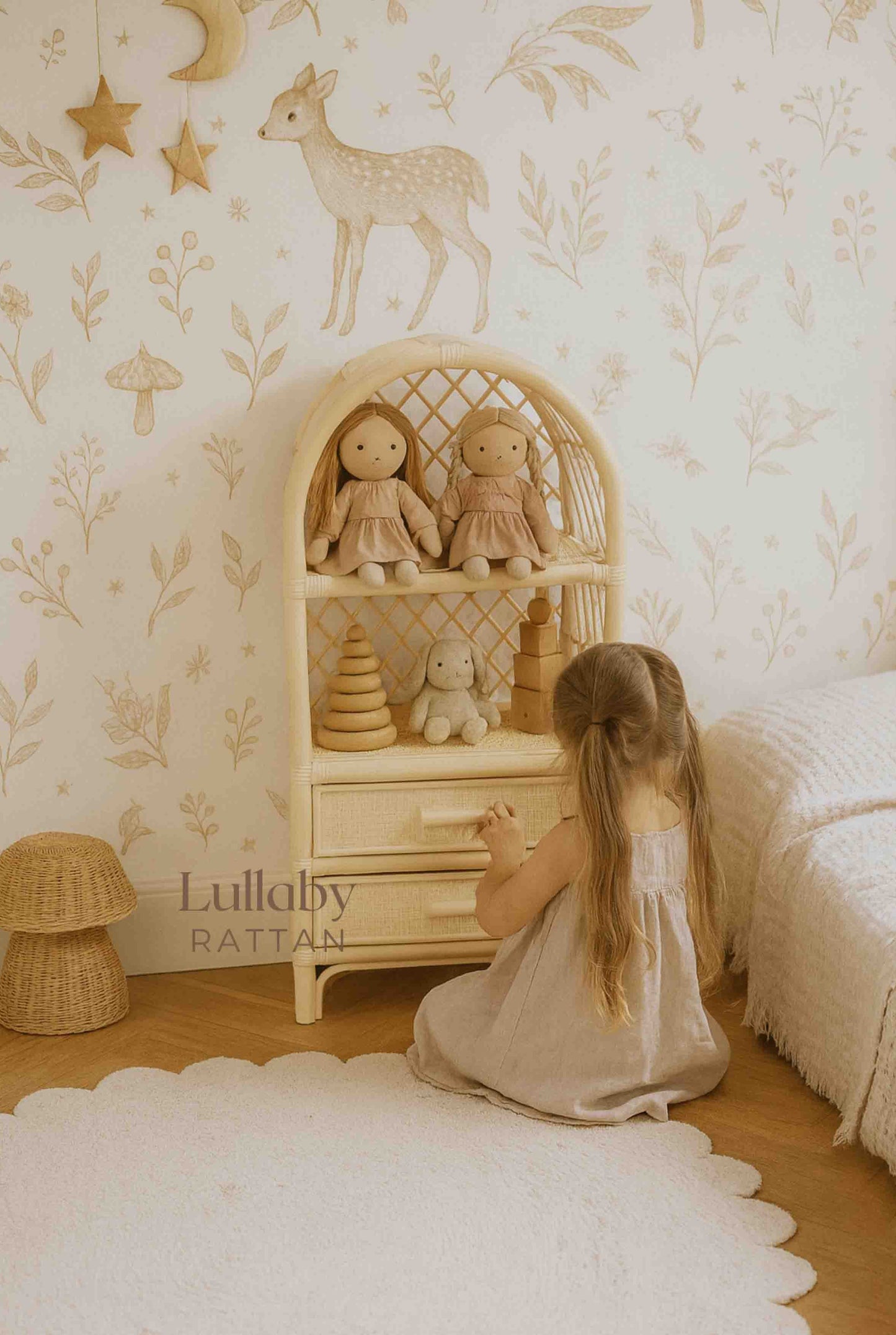 Little girl playing in a boho nursery with a rattan doll storage shelf and eco-friendly toys