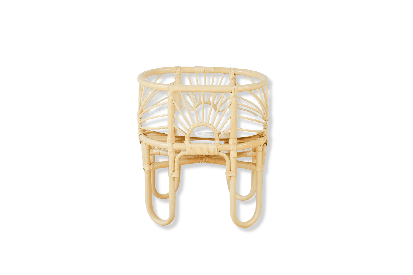 A rattan made dolls bed with sunrise shaped arches sits with a cushion and a white background.