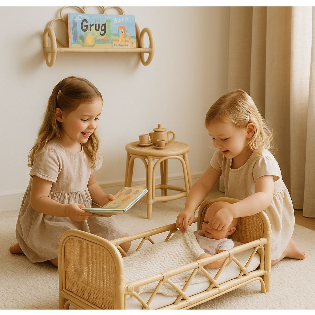 Two young girls playing with a doll crib in a room with a shelf and toys. They read a kids book called Grug to a doll laying in a play bed under a blanket.