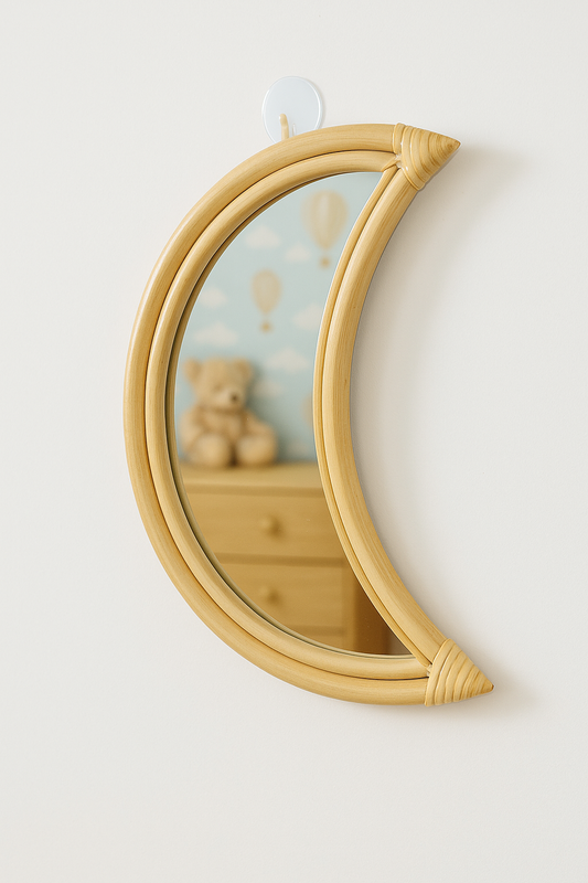 Crescent moon-shaped mirror on a wall with a reflection of a teddy bear and dresser.