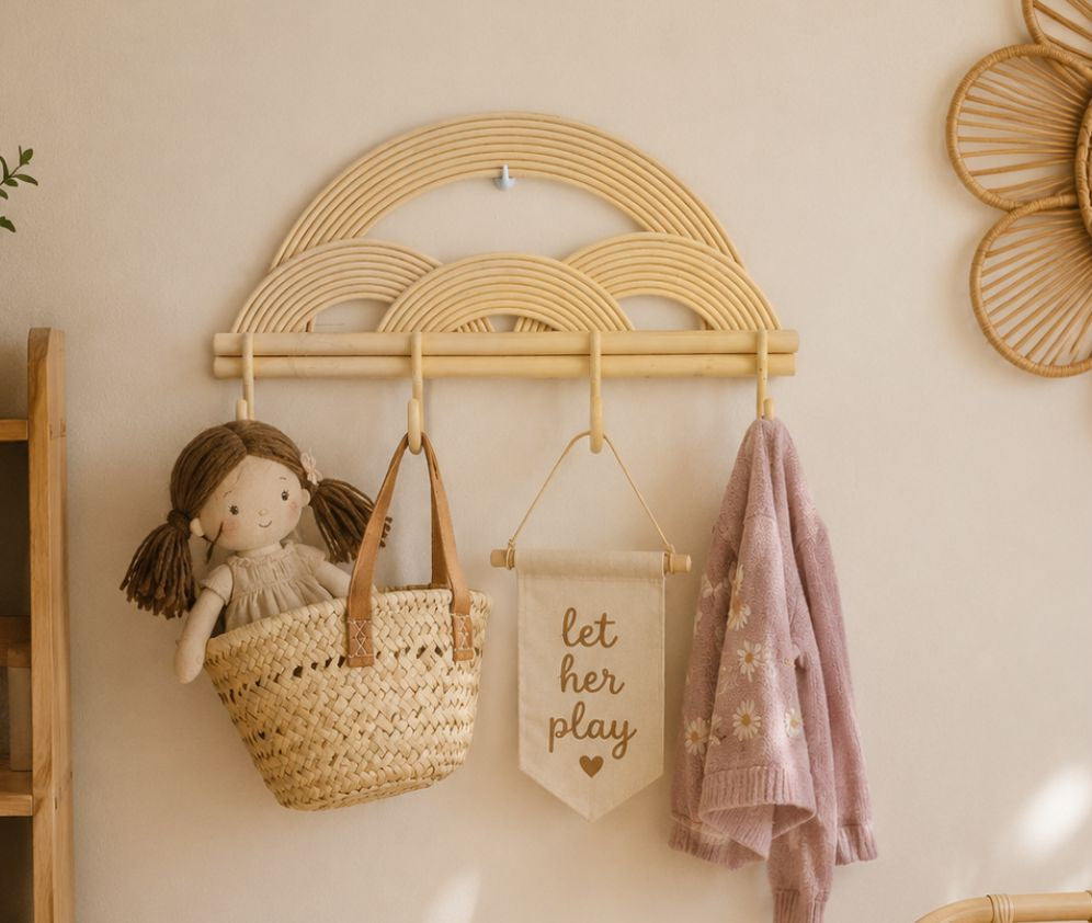 Woven cloud-shaped wall hook with a doll, bag, and towel on a light beige wall.