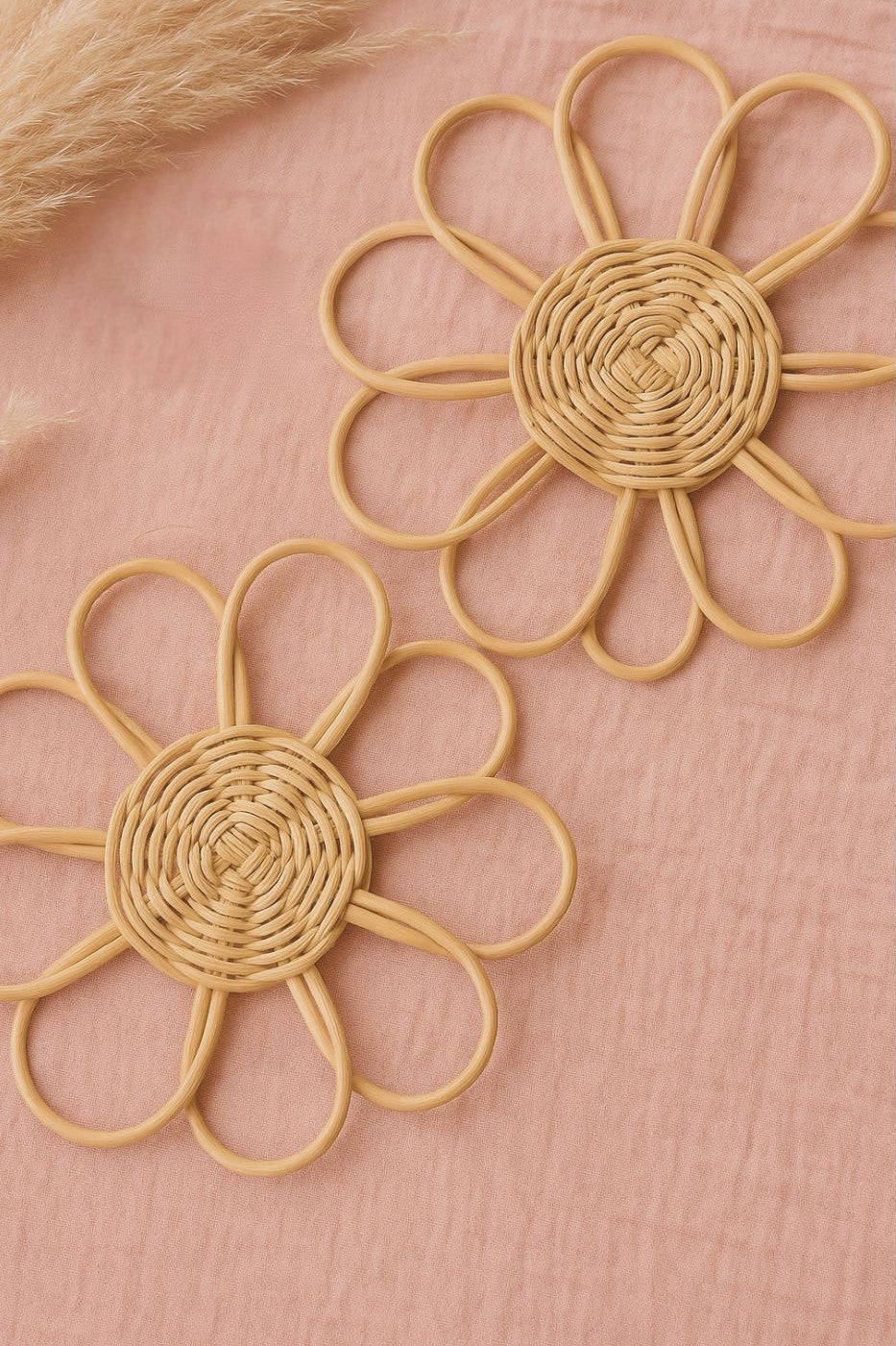 Pair of woven sunflower-shaped earrings on a pink background