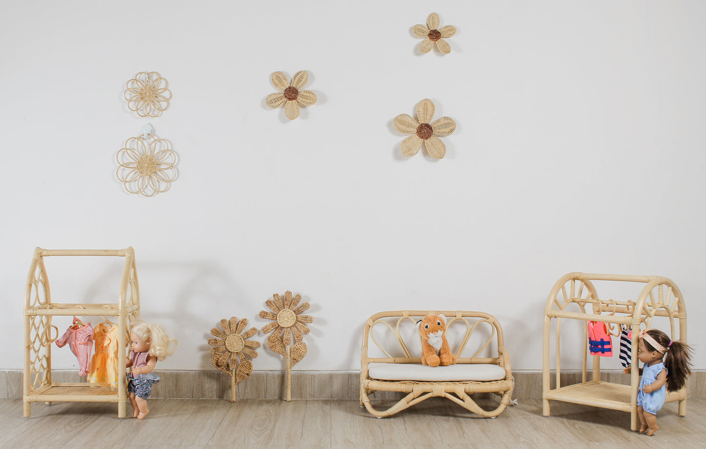 Children's room with wooden furniture and decorative flowers on the wall. Doll toys and doll clothes. Plush toys sit on a doll sized sofa. Flower decor. Fake flowers. Girls room flower decoration. 