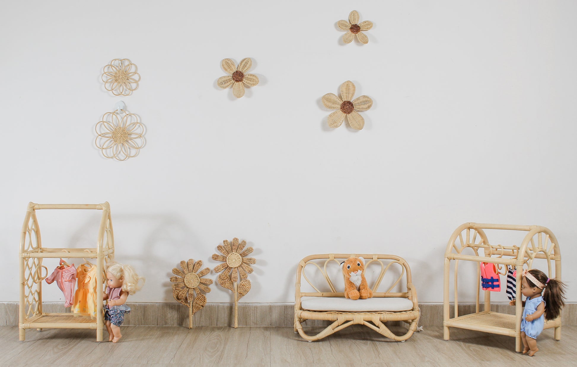 Children's room with wooden furniture and decorative flowers on the wall. Doll toys and doll clothes. Plush toys sit on a doll sized sofa. Flower decor. Fake flowers. Girls room flower decoration. 