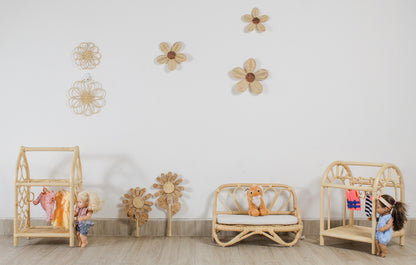 Children's room with wooden furniture and decorative flowers on the wall. Doll toys and doll clothes. Plush toys sit on a doll sized sofa. Flower decor. Fake flowers. Girls room flower decoration. 