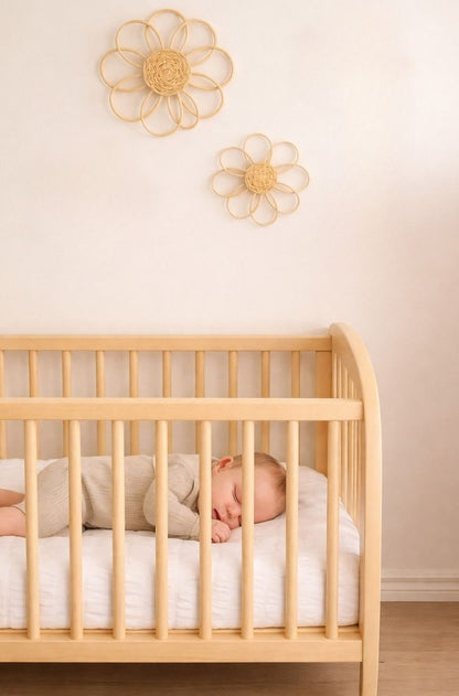 Handmade rattan flower wall decor styled in a soft neutral girls nursery with wooden toys