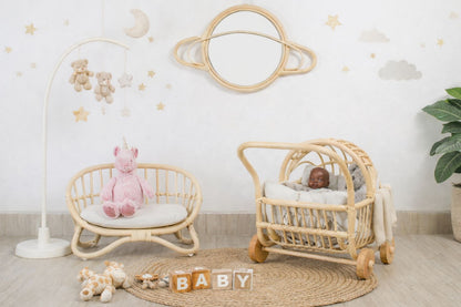The miniature rattan couch is the centerpiece, with a friendly brown doll sitting in a toy stroller next to the doll sofa. This scene captures a cozy, inviting corner of a child’s room, showing how it functions as both kids toys and stylish room accents.
