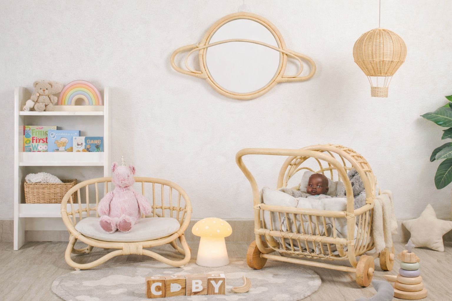 A close-up view of the white linen cushion on the miniature rattan love seat. Resting on the cushion are tiny, curated details: a fabric-bound miniature book titled "Dolly's Tales" and a delicate, blue-and-white floral patterned teacup and saucer, creating a perfect vignette for toys and games.