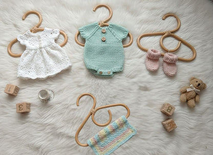 doll and baby clothes hanging off small coat hangers