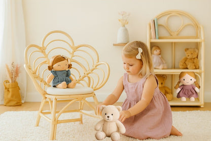 Child playing with a teddy bear in a room with a wicker chair and shelves.