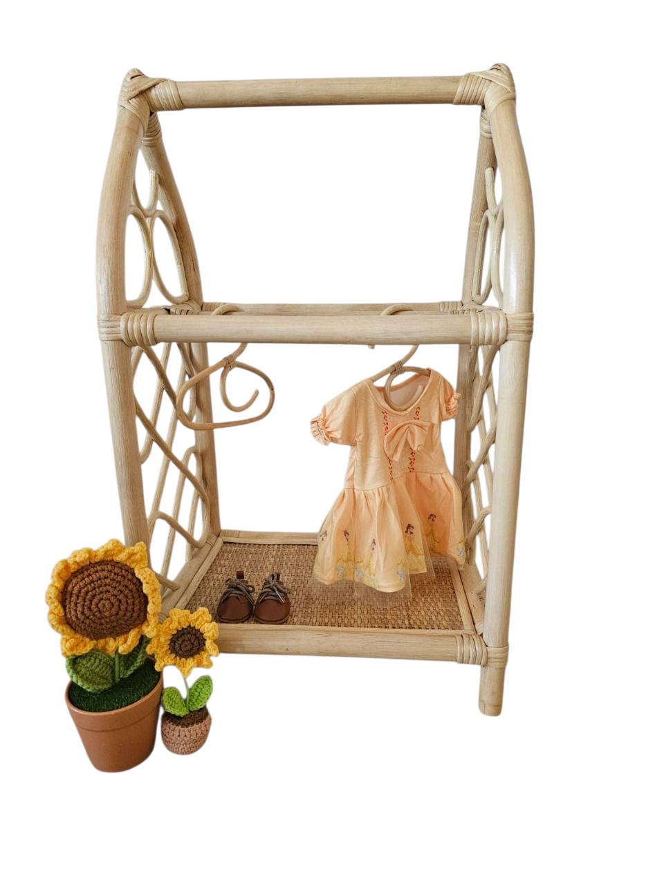 Wicker clothing rack with a dress, shoes, and decorative items on a white background for little girls imagination. 