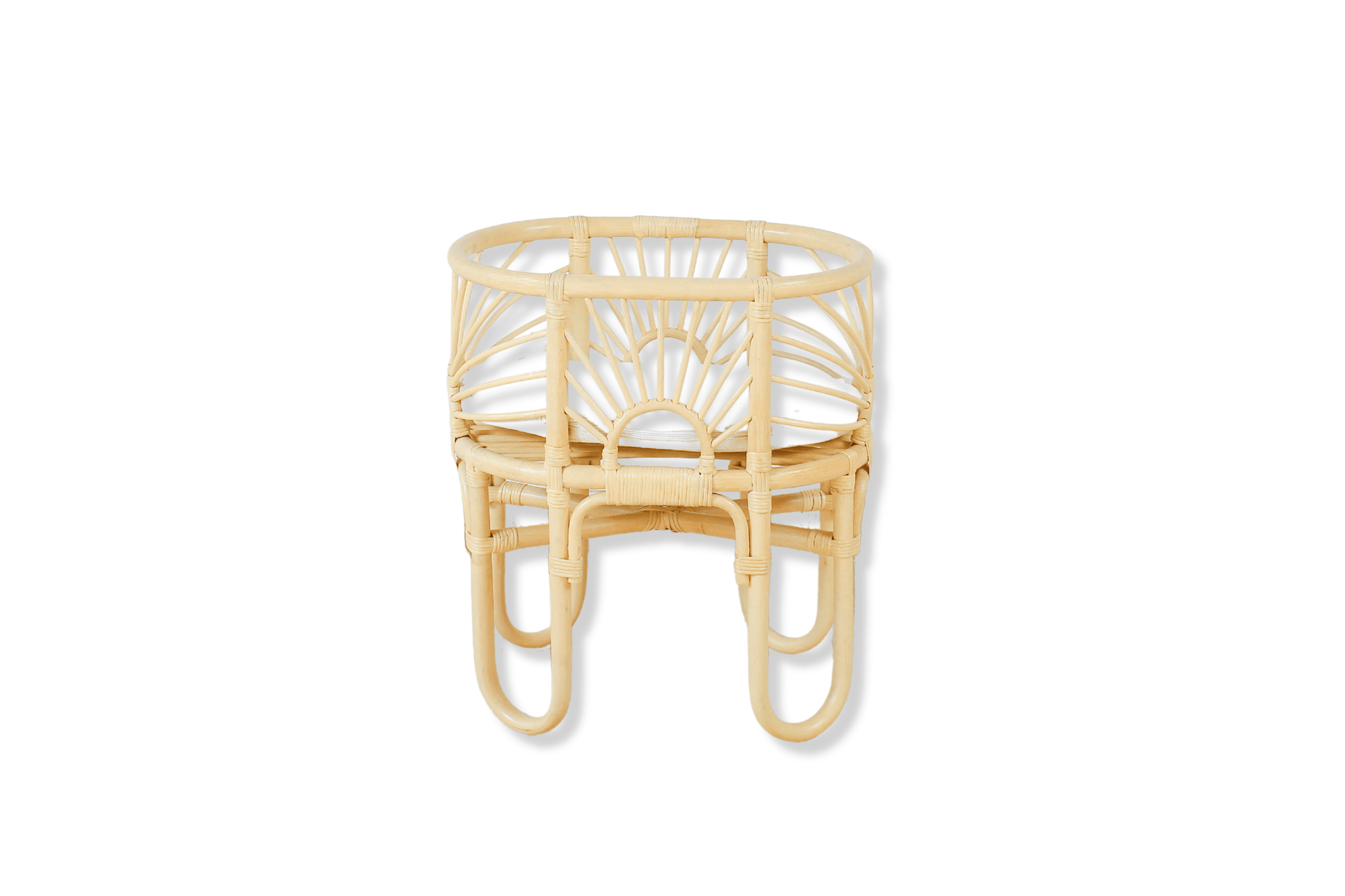 A rattan made dolls bed with sunrise shaped arches sits with a cushion and a white background. 