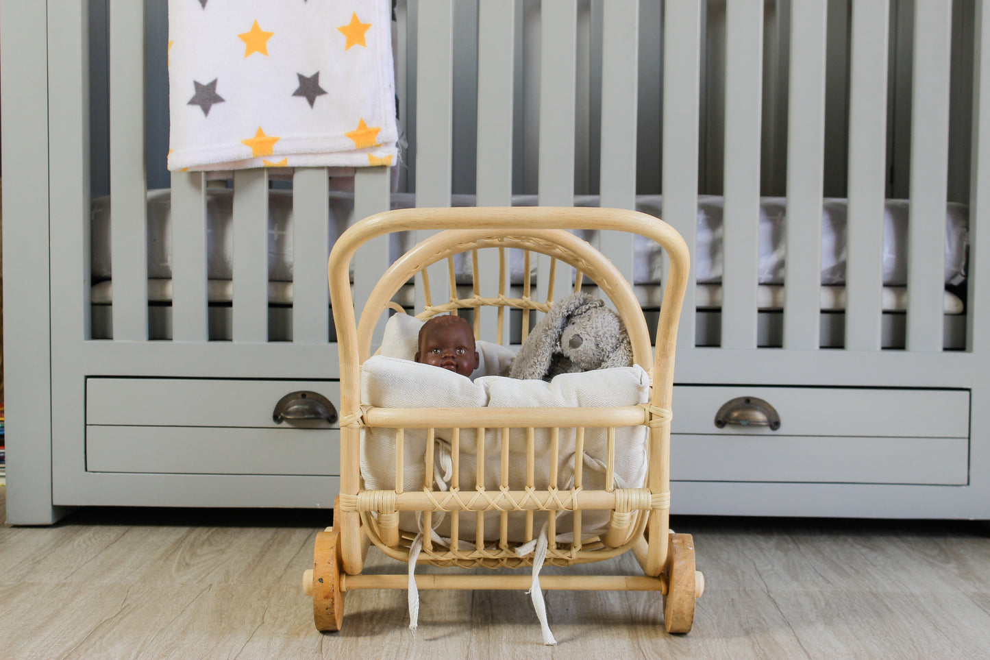 Wicker crib with baby doll and stuffed animals in a nursery setting