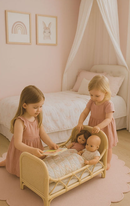 Two young girls playing with dolls in a bedroom. They play with a dolls bed made from rattan. It is in a pink room