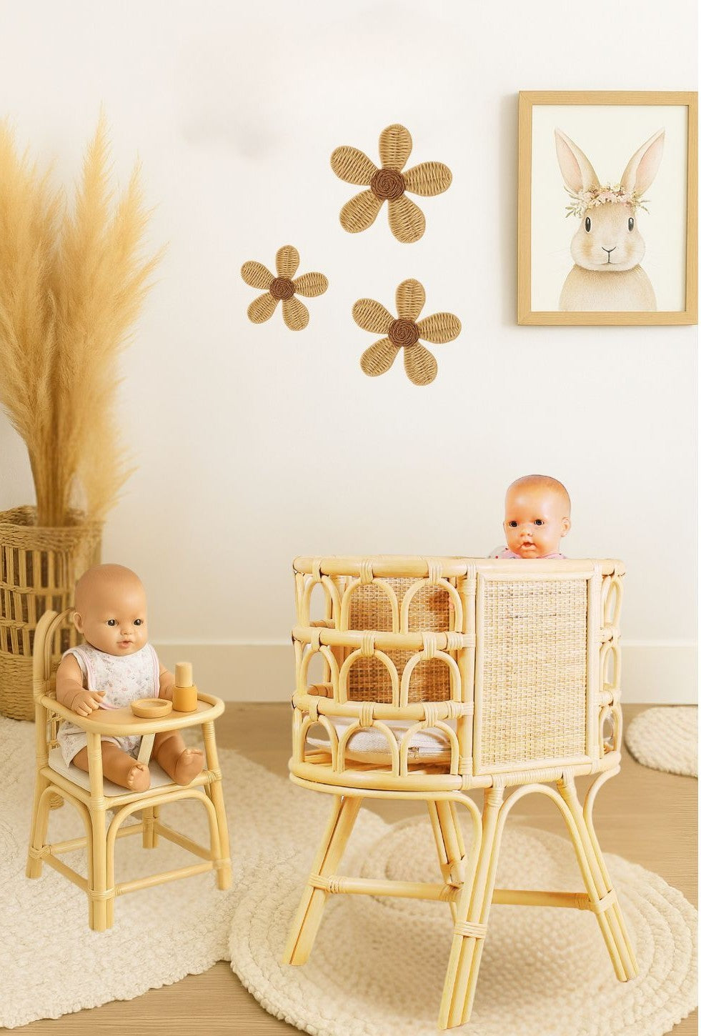 Two baby dolls in rattan high chairs with decorative flowers and a rabbit picture on the wall. Montessori playroom for kids who want to play with natural and eco-friendly toys