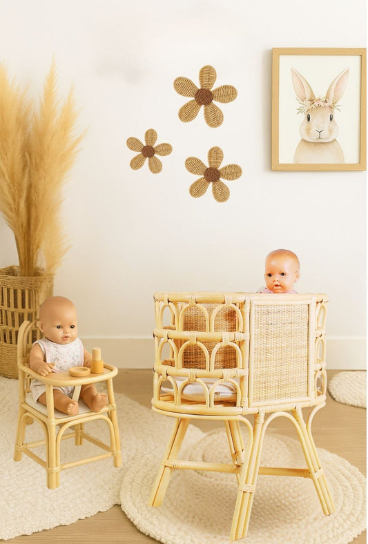 Two baby dolls in rattan high chairs with decorative flowers and a rabbit picture on the wall. Montessori playroom for kids who want to play with natural and eco-friendly toys