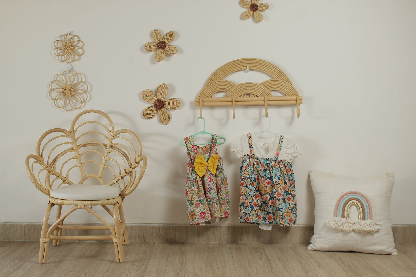 Children's room with floral dresses on hangers, a wicker chair, and decorative wall elements.