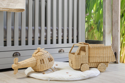 Wicker toy truck and helicopter on a wooden floor with a crib in the background. Good for toddler play. 