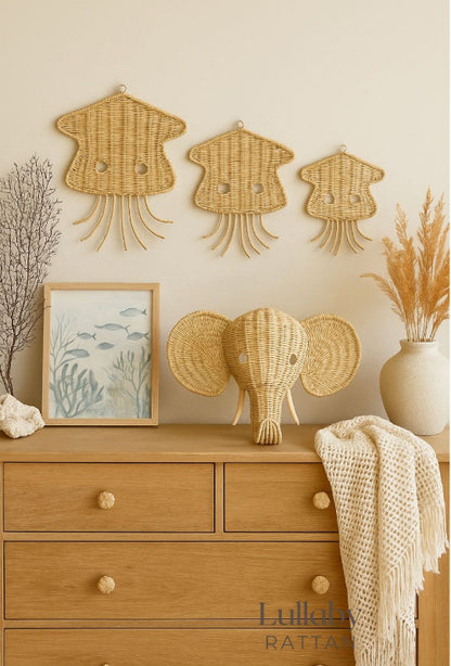 Wicker elephant head on a wooden dresser with wall decorations and a vase. Jellyfish wall decor for ocean apartment or boho vibe