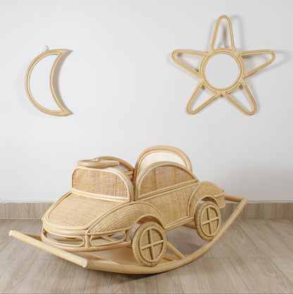 Wooden rocking car toy on a wooden floor with decorative wall items.
