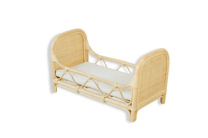 A hand-made dolls bed with a mattress sits with a white background. 