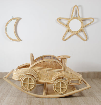 Wooden rocking car toy on a wooden floor with decorative wall items.