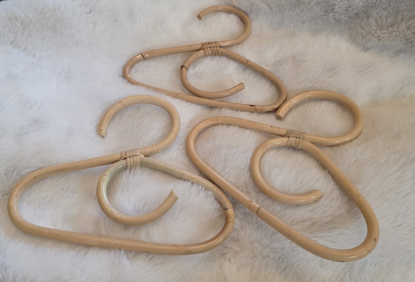 3 coat hangers laying on a cosy sheep skin rug. 