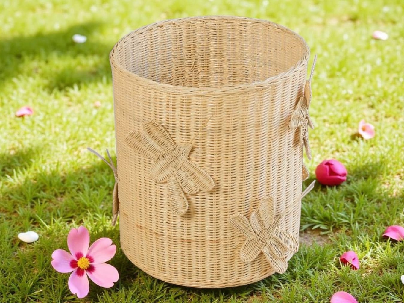 Wicker basket with dragonfly design on grass with flowers