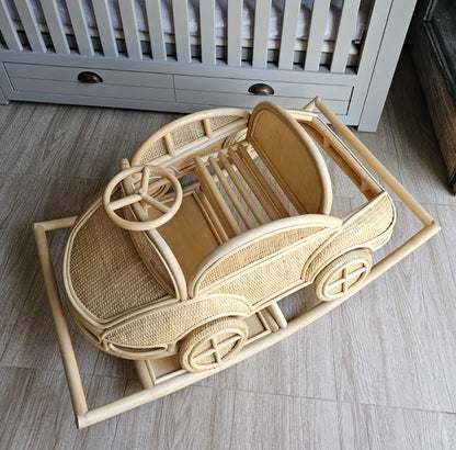 Wooden toy car on a wooden floor with a crib in the background