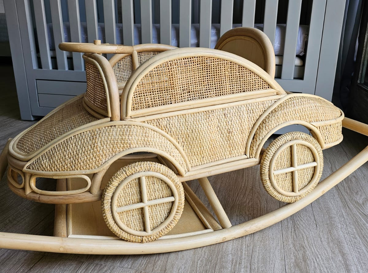 Wicker baby car seat on a wooden floor with a crib in the background
