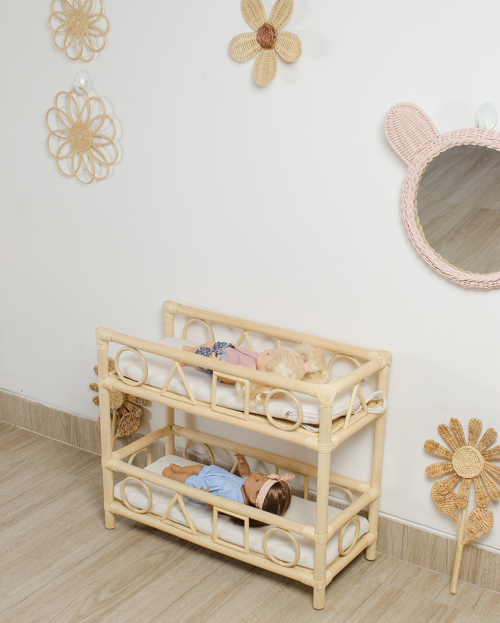 Wooden crib with baby dolls in a room with decorative flowers on the wall.