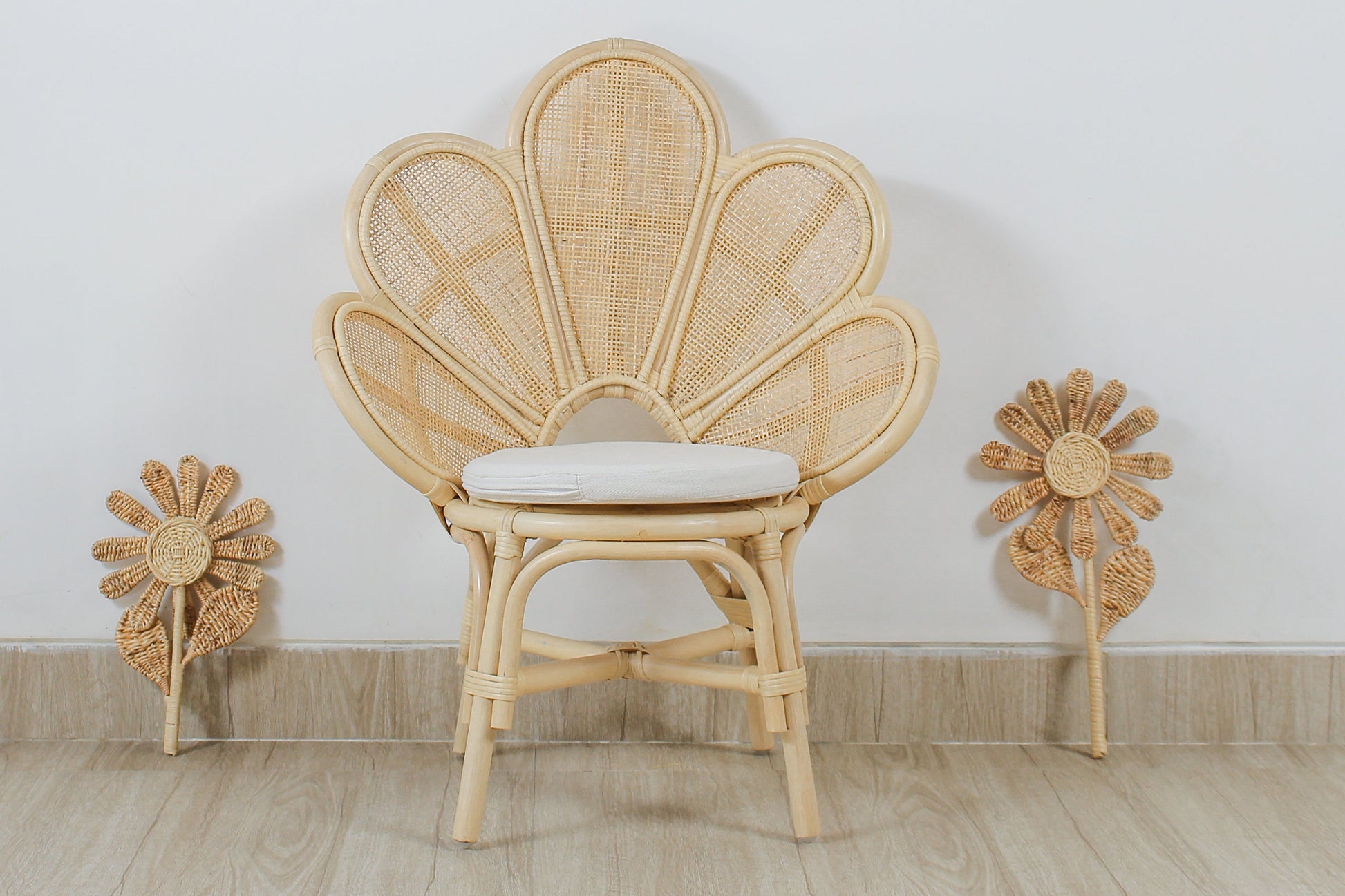 Wicker chair with a cushion on a wooden floor against a white wall. A girls bedroom decorative chair. Flower design. Rattan chair. Flower decoration. 